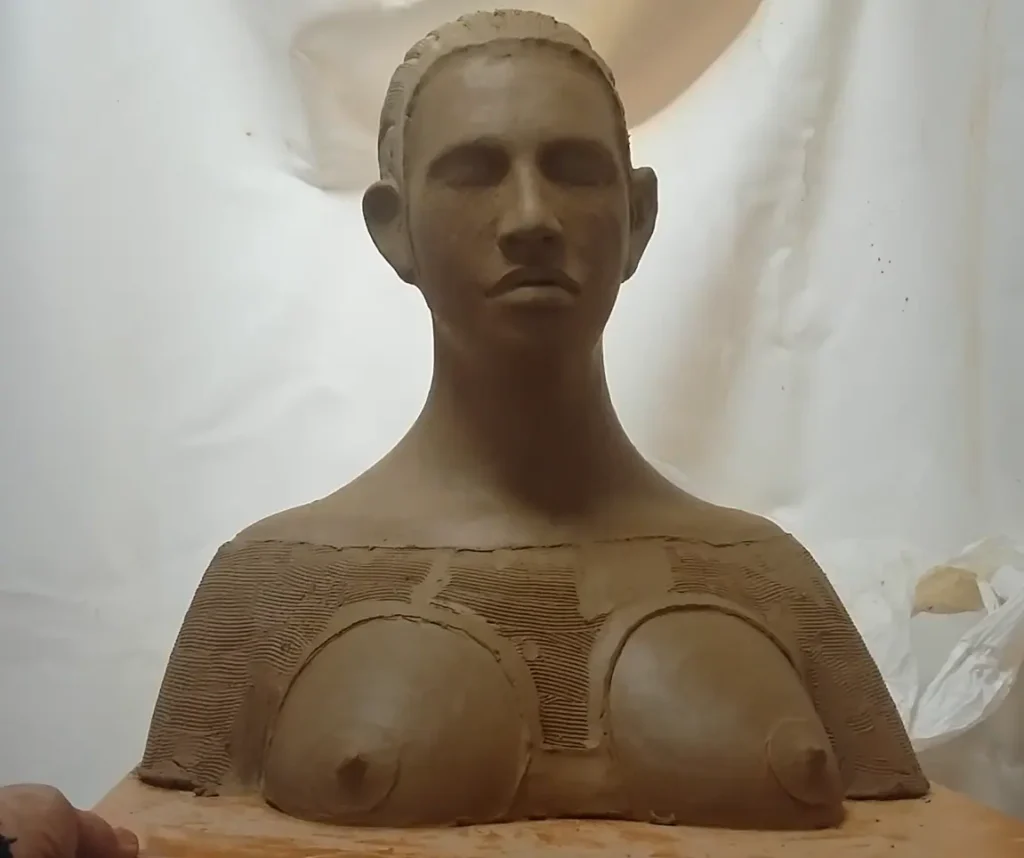 Escultura simbólica de mujer con pectoral tribal, obra en barro que evoca fuerza interior