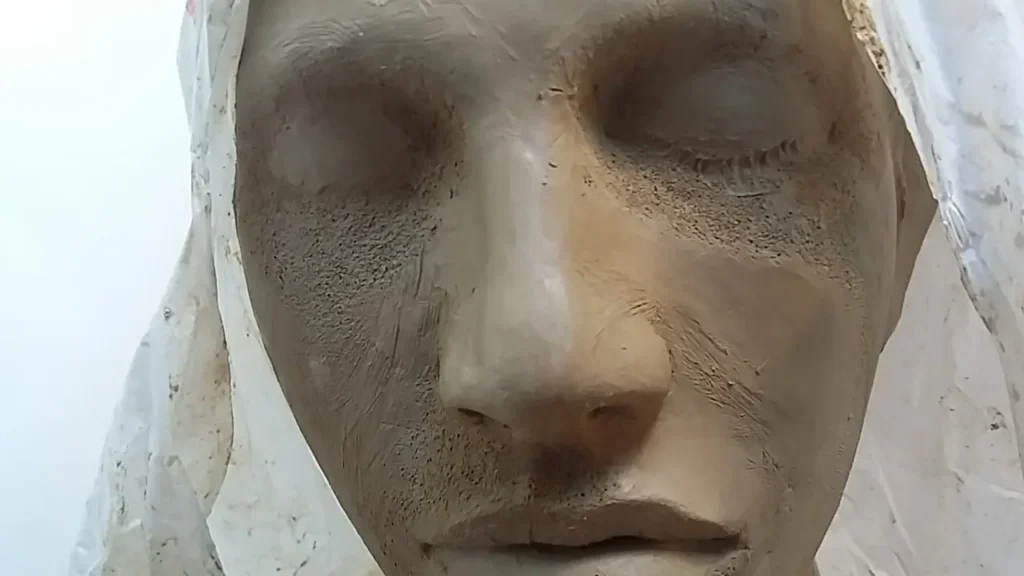 Detalle del rostro andrógino y sereno de la escultura Nodriza Eónica, lucha silenciosa en el barro